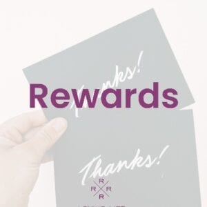 A hand holding up two cards with the word " rewards " on them.