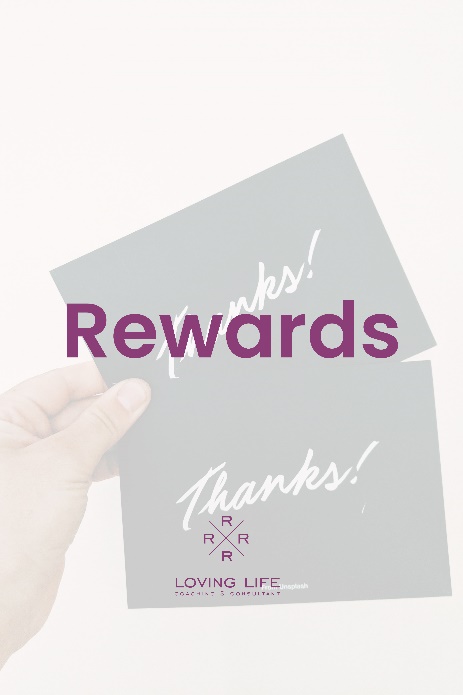 A hand holding up two cards with the word " rewards " on them.